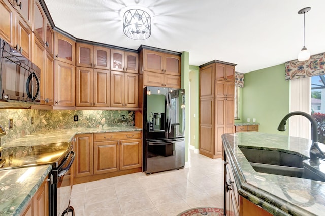 kitchen with glass insert cabinets, brown cabinets, decorative light fixtures, black appliances, and a sink