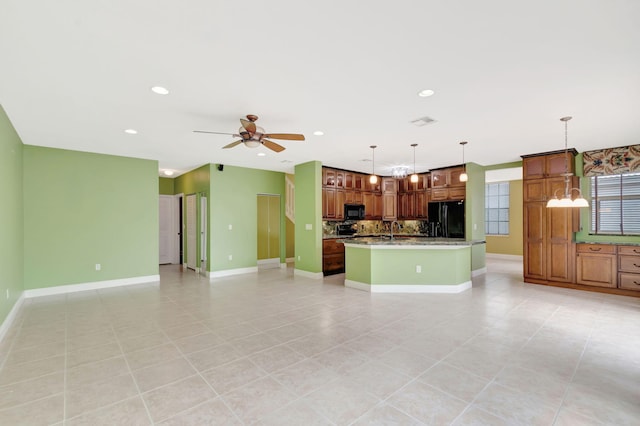 kitchen featuring black appliances, a kitchen island with sink, brown cabinetry, and decorative light fixtures