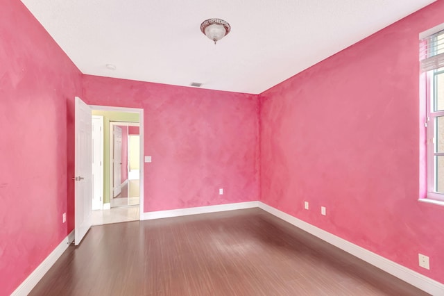 unfurnished room with visible vents, baseboards, and dark wood-type flooring