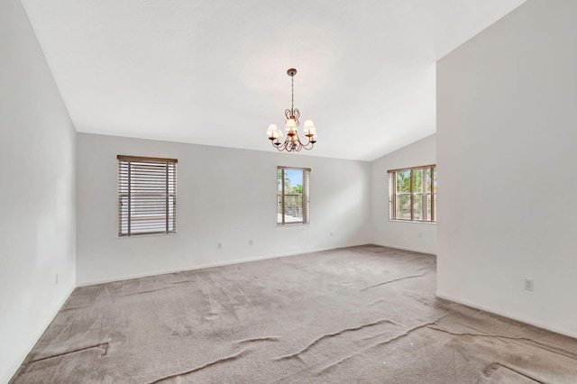 carpeted empty room with lofted ceiling, baseboards, and an inviting chandelier