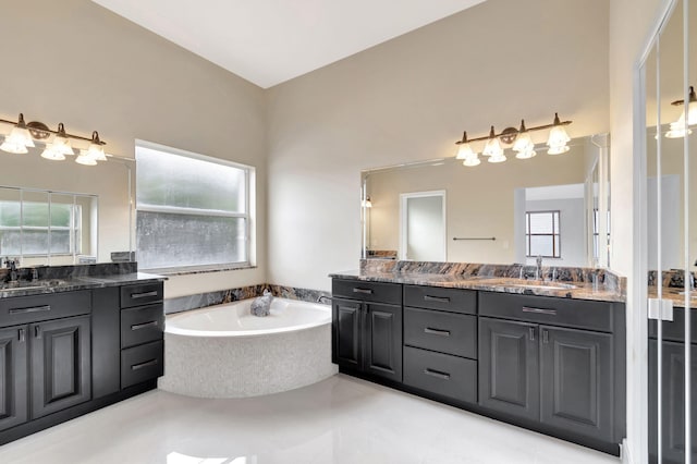 full bathroom featuring plenty of natural light, two vanities, a sink, and a bath