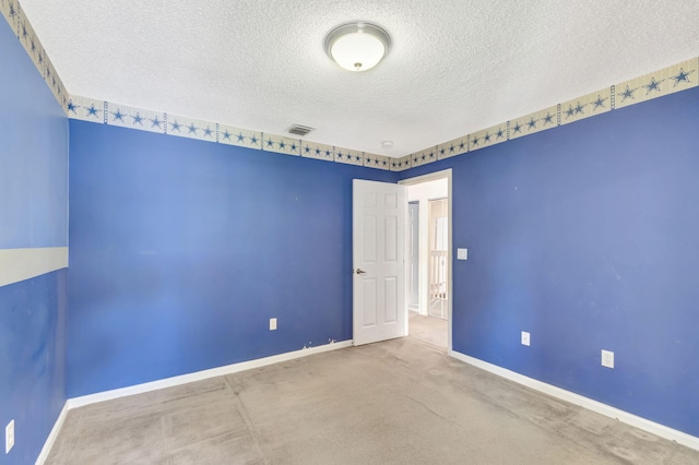 carpeted spare room with baseboards, visible vents, and a textured ceiling