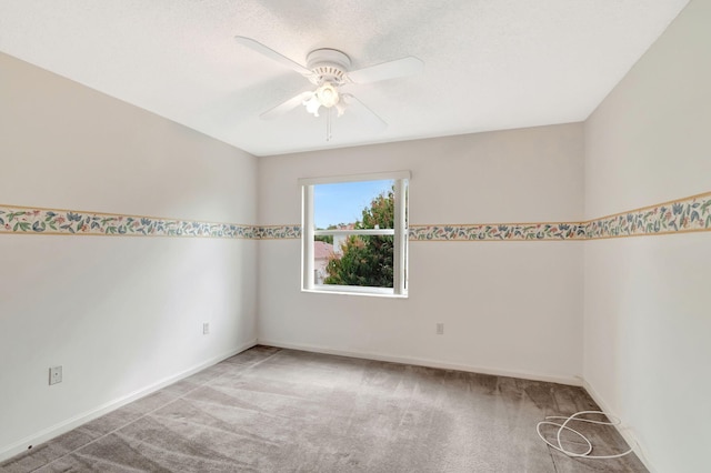 spare room with light carpet, a textured ceiling, a ceiling fan, and baseboards