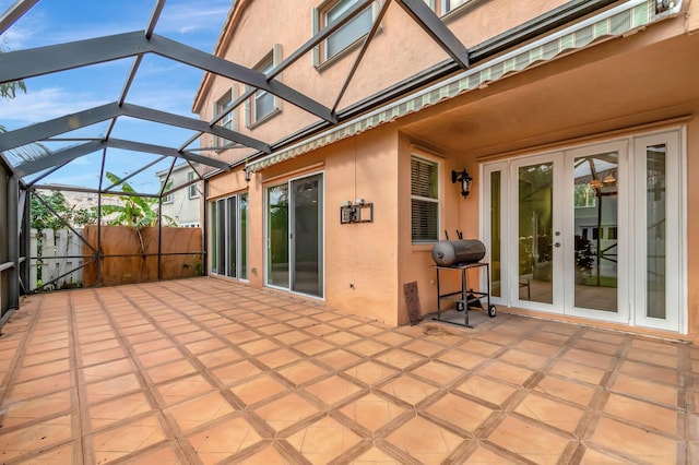 view of patio / terrace featuring french doors, glass enclosure, and fence