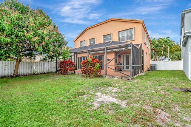 back of house with glass enclosure, central AC unit, a fenced backyard, a yard, and stucco siding