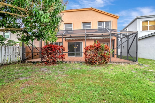 rear view of property featuring a lawn, fence, a lanai, and stucco siding