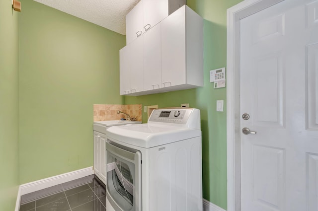 clothes washing area featuring a textured ceiling, dark tile patterned floors, a sink, cabinet space, and washer / clothes dryer