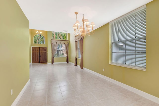 spare room featuring baseboards, light tile patterned floors, and a notable chandelier