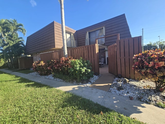 view of side of home with a lawn and a balcony