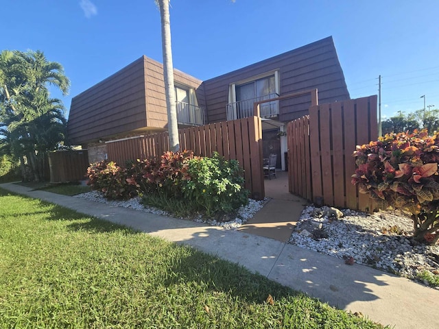 view of home's exterior featuring a balcony and a yard