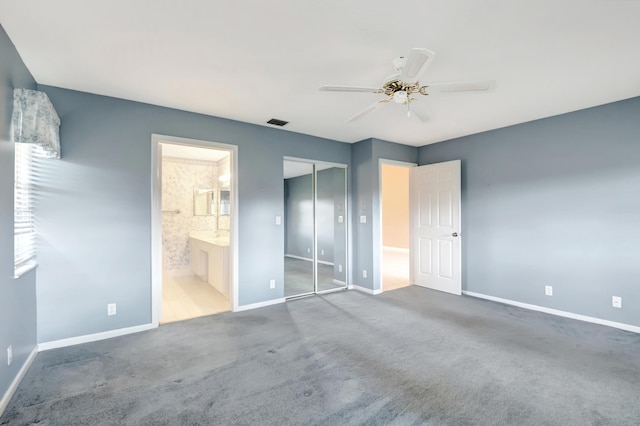 unfurnished bedroom featuring a closet, carpet flooring, connected bathroom, and ceiling fan