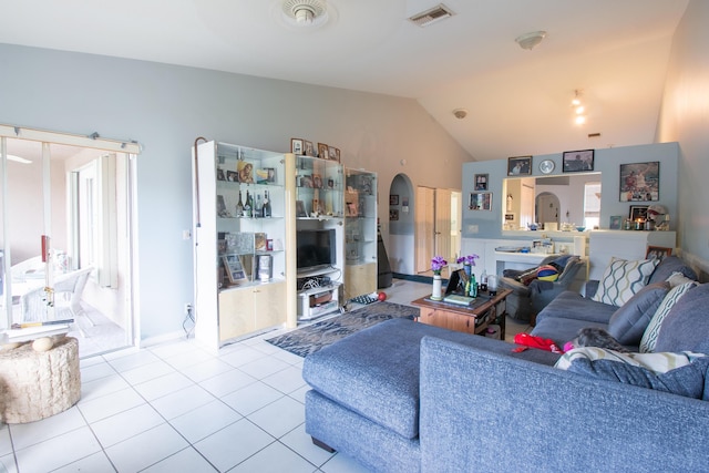 living area featuring tile patterned flooring, visible vents, and vaulted ceiling