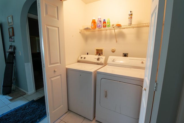 laundry room with arched walkways, laundry area, light tile patterned floors, and washing machine and clothes dryer