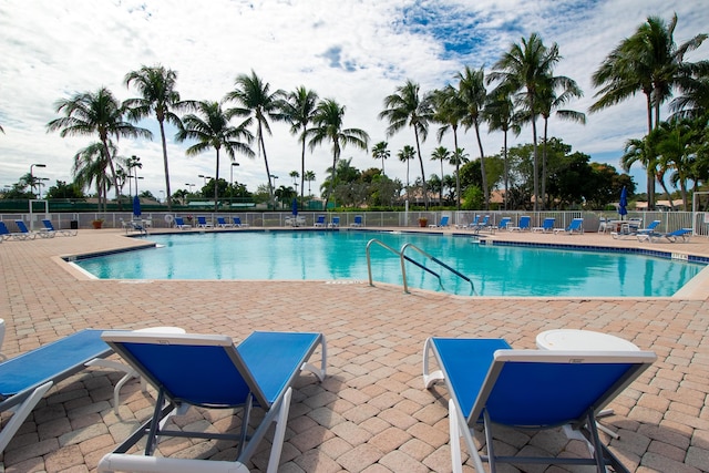 pool with a patio area and fence