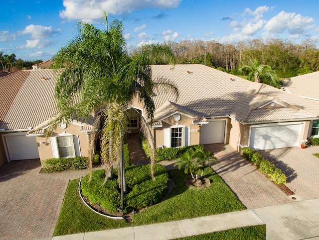 view of front facade with driveway, an attached garage, a tile roof, and stucco siding