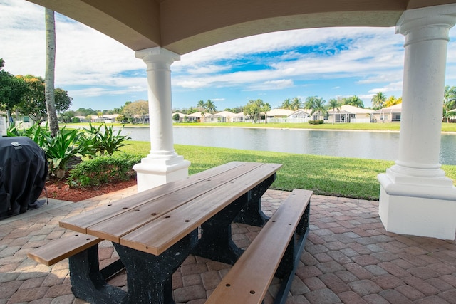 view of patio featuring outdoor dining area, a water view, and a grill