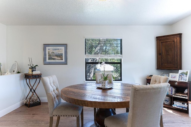 dining space with a textured ceiling and light wood-type flooring