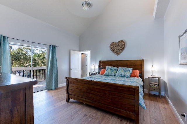 bedroom with access to exterior, light hardwood / wood-style floors, and high vaulted ceiling