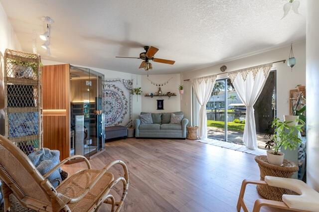 sitting room with ceiling fan, hardwood / wood-style floors, and a textured ceiling