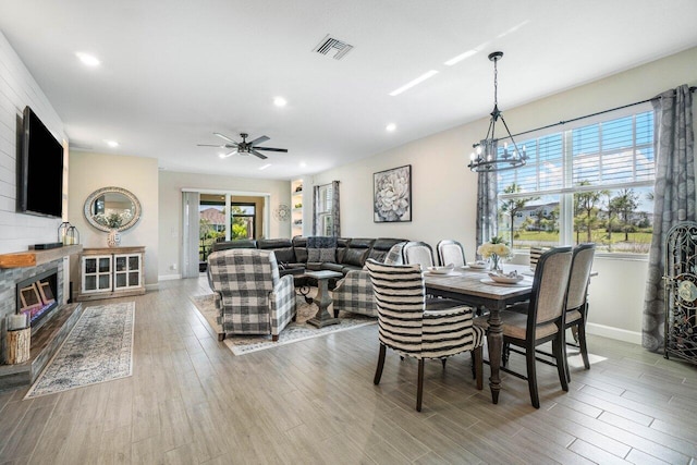 dining area featuring ceiling fan with notable chandelier and light wood-type flooring