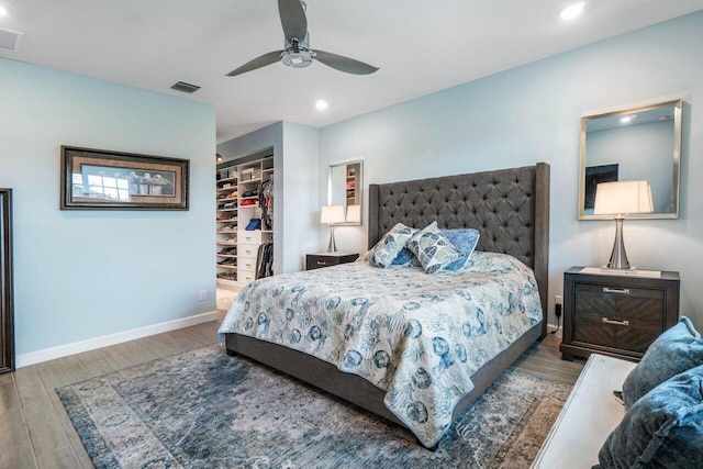 bedroom featuring a closet, dark hardwood / wood-style floors, ceiling fan, and a spacious closet