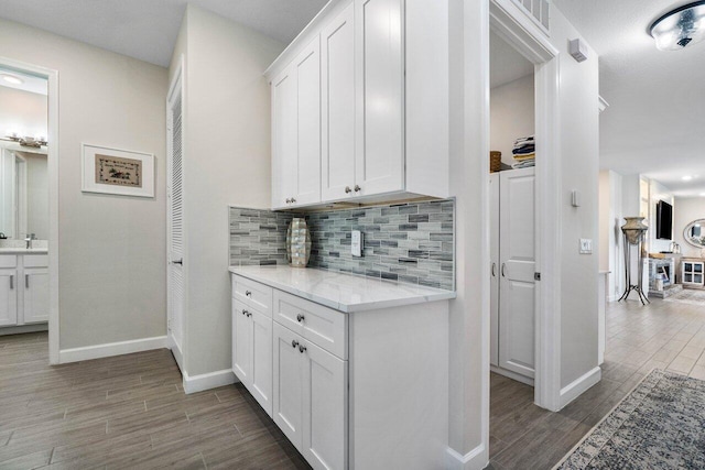 kitchen with light stone counters, backsplash, sink, and white cabinets