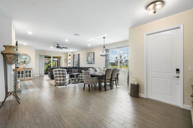 dining area with ceiling fan with notable chandelier, hardwood / wood-style floors, and a wealth of natural light