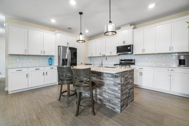 kitchen featuring white cabinetry, sink, a kitchen breakfast bar, hanging light fixtures, and stainless steel appliances