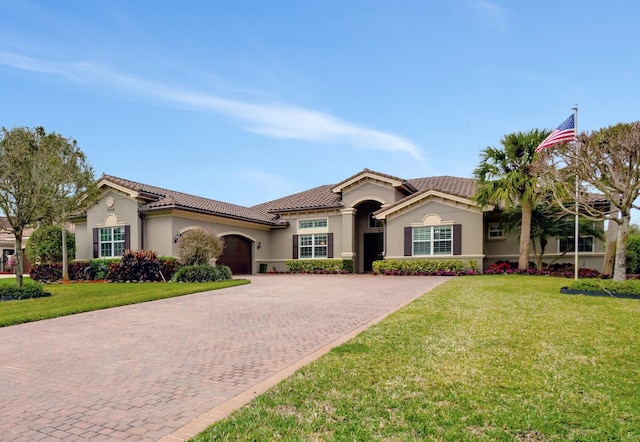 mediterranean / spanish-style house featuring a garage, a tile roof, decorative driveway, and a front yard