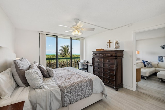 bedroom featuring light wood-type flooring, access to exterior, floor to ceiling windows, and ceiling fan