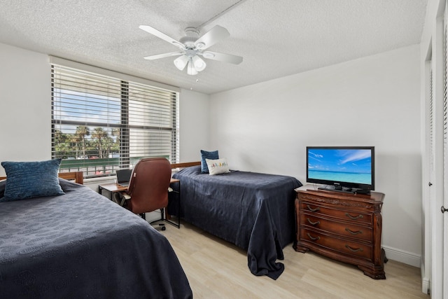 bedroom with a textured ceiling, ceiling fan, and light hardwood / wood-style flooring