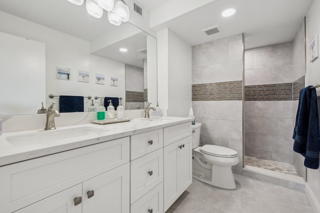 bathroom featuring toilet, tiled shower, tile patterned flooring, and vanity