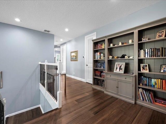 hall featuring dark wood-type flooring and a textured ceiling