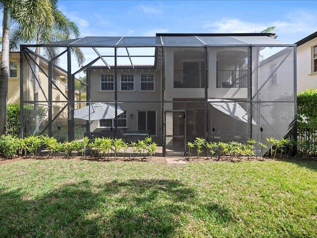 back of house featuring a lawn, a balcony, and glass enclosure