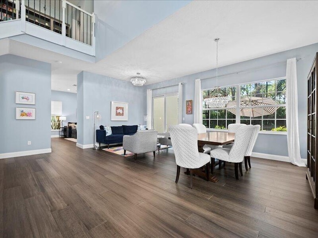 dining space featuring a notable chandelier, a towering ceiling, and dark wood-type flooring