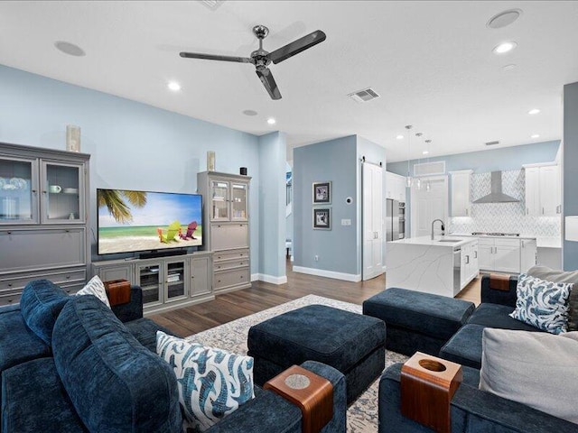 living room featuring ceiling fan, dark hardwood / wood-style floors, and sink