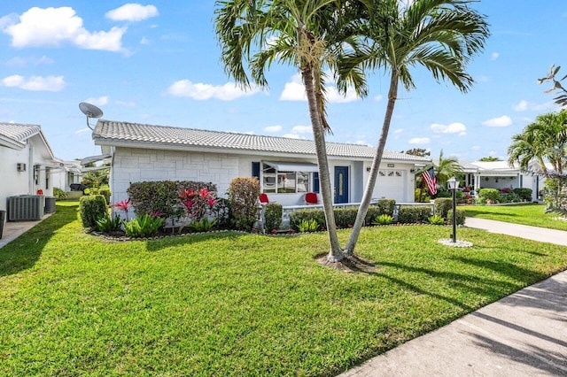 ranch-style home featuring a garage, cooling unit, and a front yard