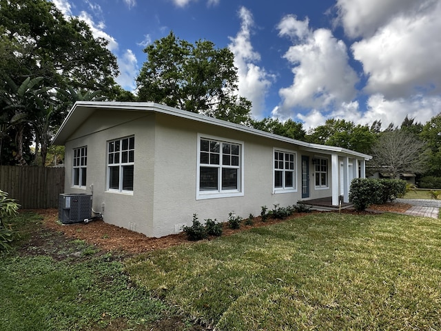 ranch-style home featuring central AC unit and a front lawn