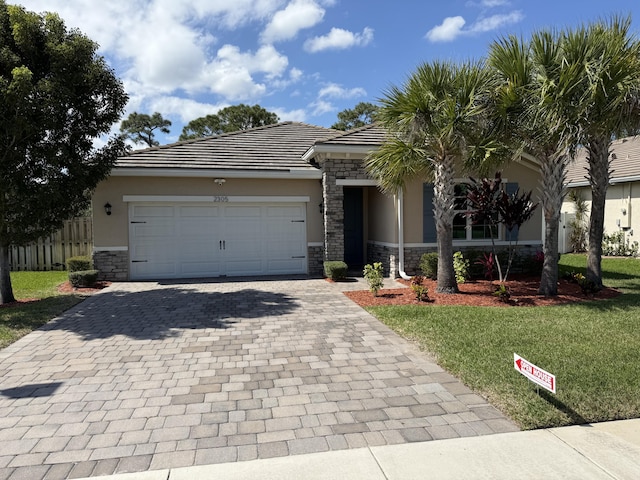 view of front of property with an attached garage, stone siding, decorative driveway, stucco siding, and a front lawn