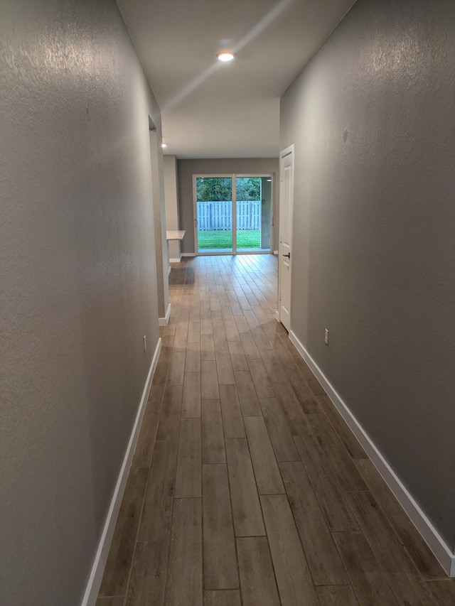 corridor with baseboards, dark wood-style flooring, and a textured wall