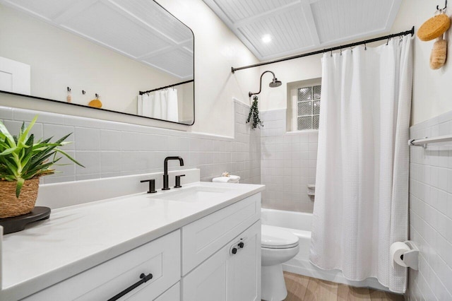 bathroom featuring shower / bath combo, wainscoting, toilet, vanity, and tile walls