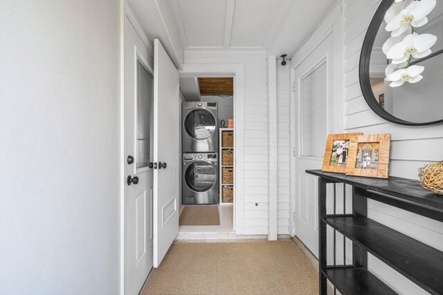 corridor featuring light carpet and stacked washer and clothes dryer