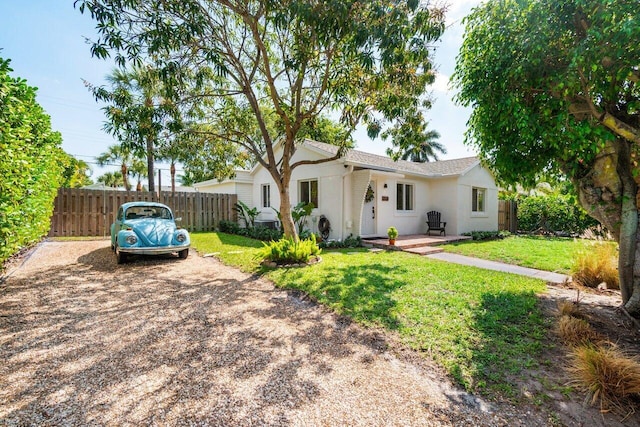 single story home featuring driveway, fence, a front lawn, and stucco siding