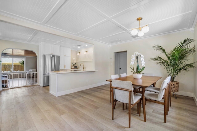 dining area featuring baseboards, arched walkways, coffered ceiling, an inviting chandelier, and light wood-style floors