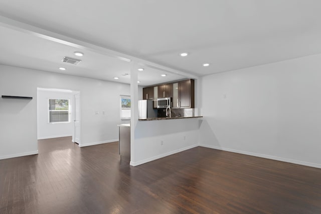 kitchen featuring a breakfast bar, dark brown cabinets, white refrigerator, dark hardwood / wood-style flooring, and kitchen peninsula