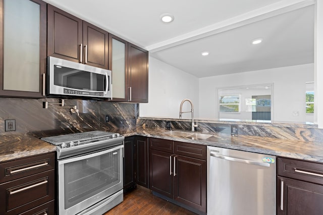 kitchen with stainless steel appliances, a healthy amount of sunlight, sink, and dark stone counters