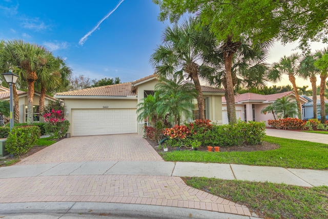 mediterranean / spanish-style home featuring a garage, a tiled roof, decorative driveway, and stucco siding