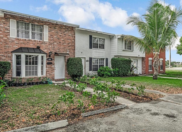 townhome / multi-family property featuring a front yard and brick siding