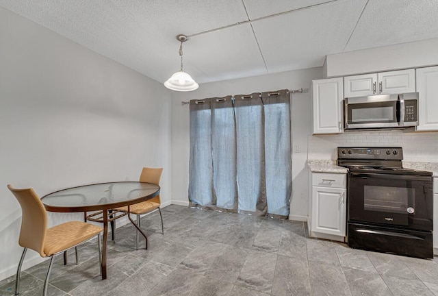 kitchen featuring tasteful backsplash, stainless steel microwave, hanging light fixtures, electric range, and white cabinets