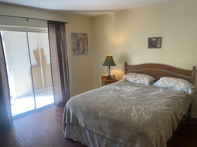 bedroom featuring access to outside, dark hardwood / wood-style floors, and a textured ceiling